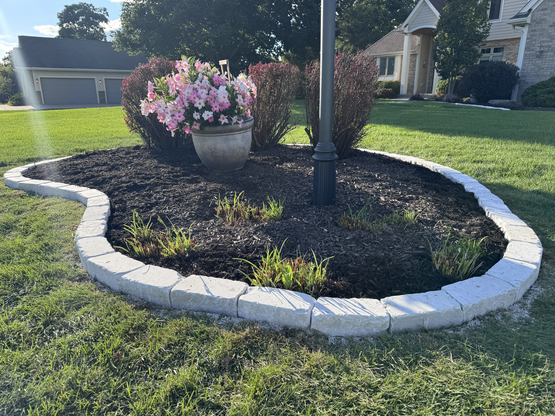 Finished curved stone edging around a planting bed with flowers