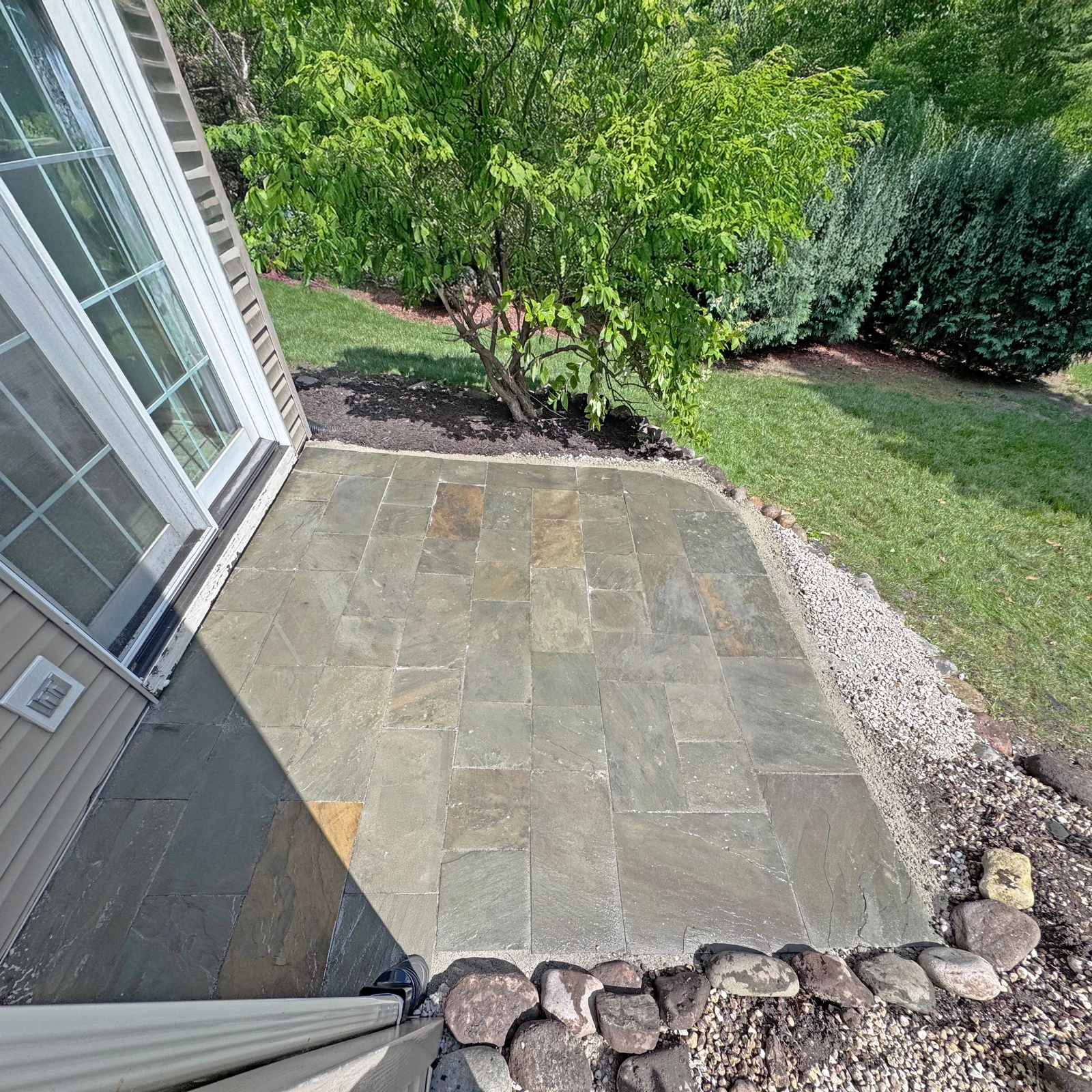 Restored patio stones beside the same sliding glass door and garden tree