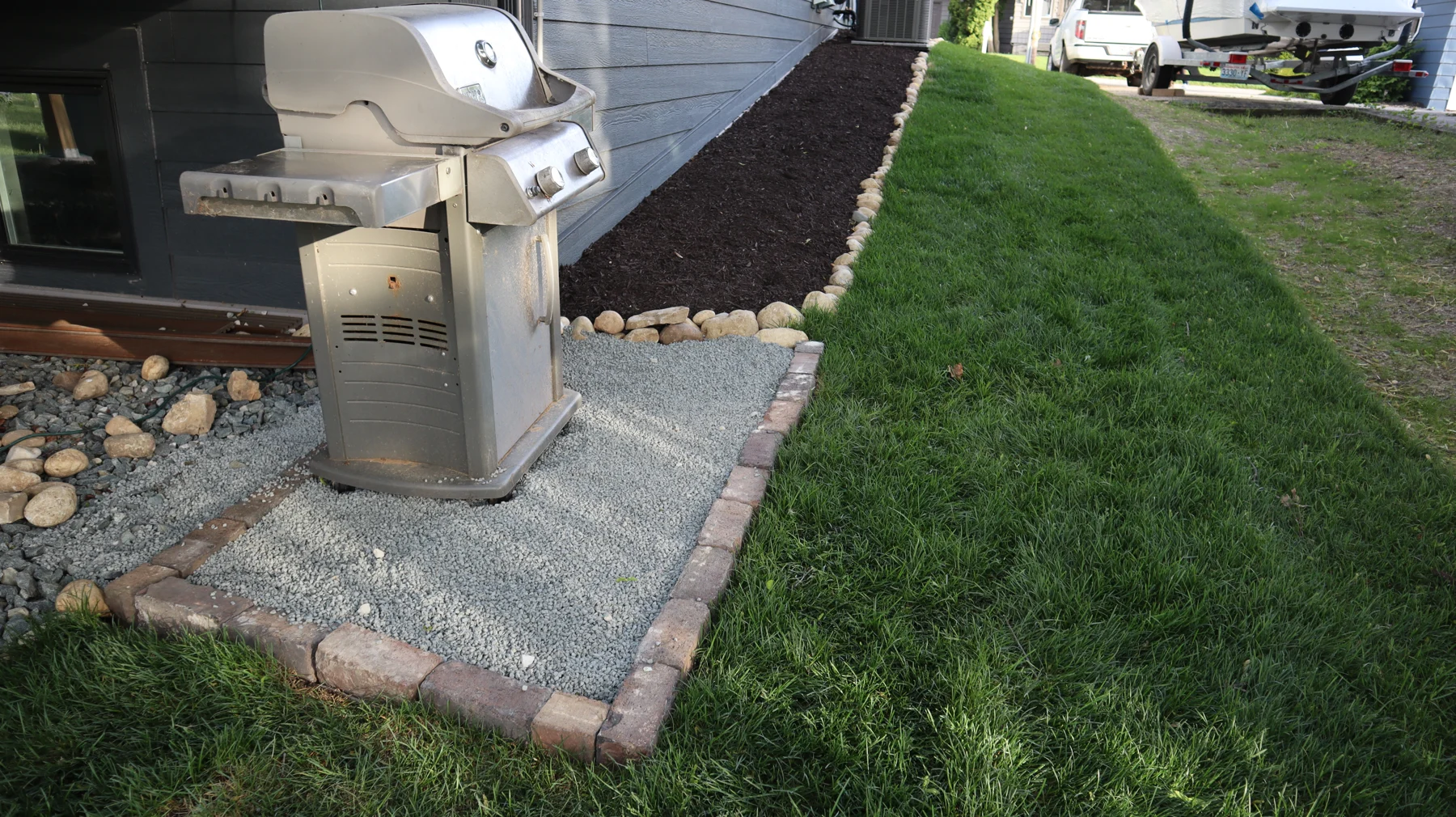 Fresh sod beside a grey house and mulched landscape bed