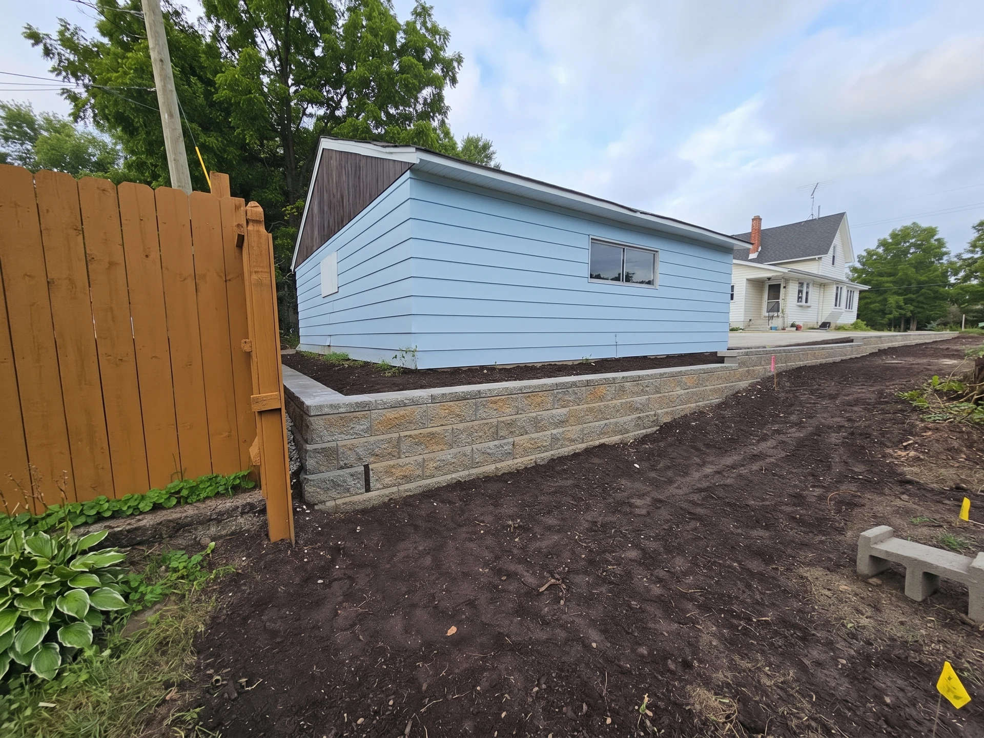 Replacement capped block retaining wall beside a blue garage in Waukesha