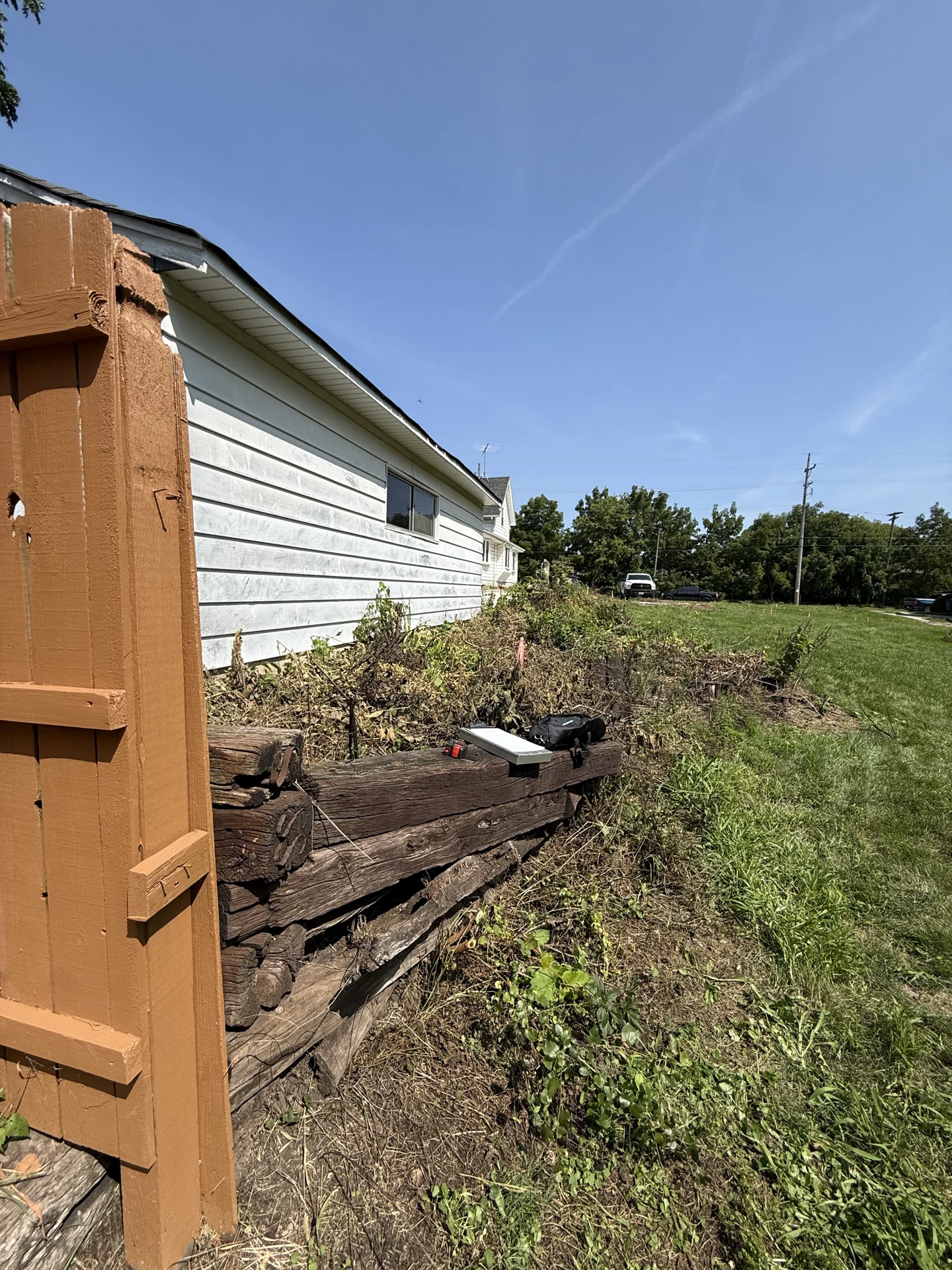 Old timber retaining wall beside the same garage and wood fence in Waukesha
